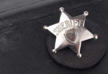 Badge-Toting Predator Exposed A silver sheriff badge resting on a black leather surface