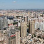 Rent Freeze Backfires? NYC’s Cost Time Bomb Aerial view of a sprawling urban city with high-rise buildings and green spaces