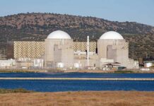 Iran Dismantles Nukes? Not So Fast Nuclear power plant with domed structures beside a water body and mountains in the background