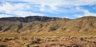 A vast desert landscape with a mountain range under a blue sky