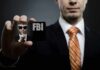Kids’ Meal Millions Vanish — FBI Pounces Abroad A man in a suit holding an FBI identification card while making a shushing gesture
