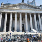 Political Violence On Trial — Not Just One Man Courthouse facade with media crews setting up outside.