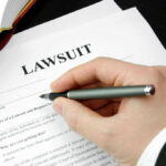Top Cop Indicted — Courtroom Mayhem Ensues Hand holding pen, filling out lawsuit form.