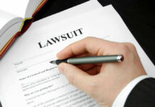 Top Cop Indicted — Courtroom Mayhem Ensues Hand holding pen, filling out lawsuit form.