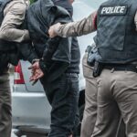 Most Wanted Down—Kingpin Found Police officers arresting a person beside a car