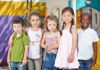 YMCA Scrubs Gender Pledge — Why Now? Five children standing together in a playground setting, smiling at the camera