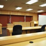 Interior view of an empty courtroom with wooden furniture and American flags