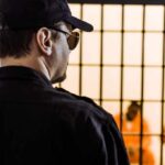 Security guard watching inmates behind jail bars