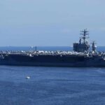 Aircraft carrier at sea with crew lining the deck