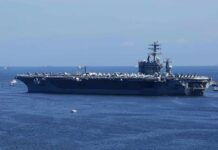 Overboard Alarms Expose Hidden Navy Crisis Aircraft carrier at sea with crew lining the deck
