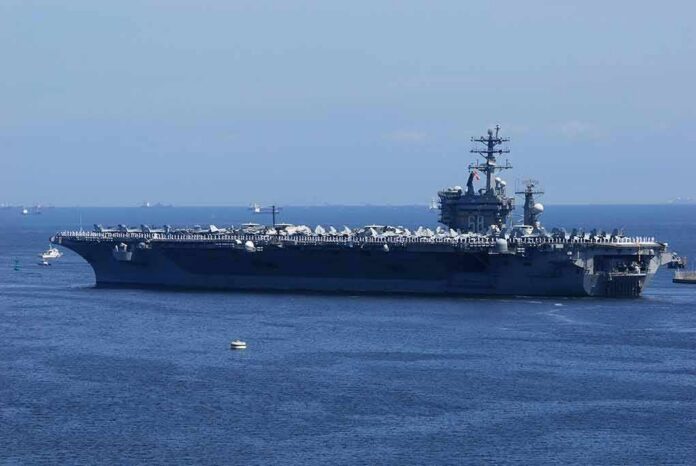 Aircraft carrier at sea with crew lining the deck