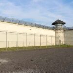Prison yard with chain-link fence and guard tower