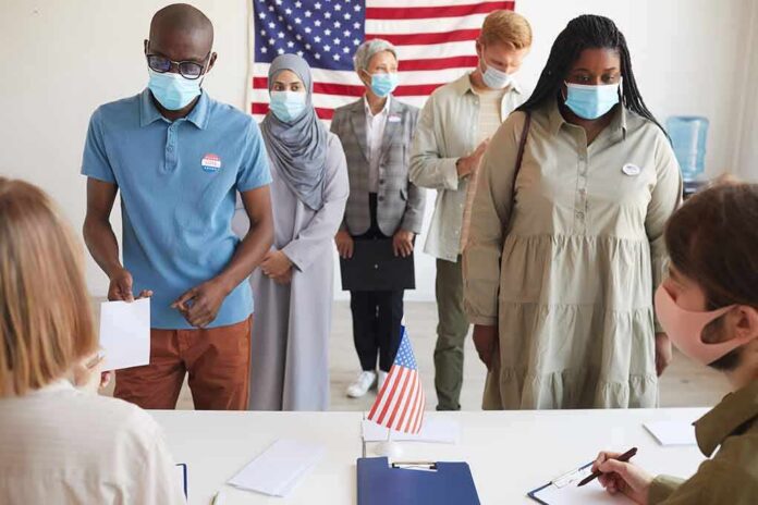 Voters wearing masks stand in line at a polling station