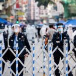Police officers in masks stand behind portable barricades on a city street