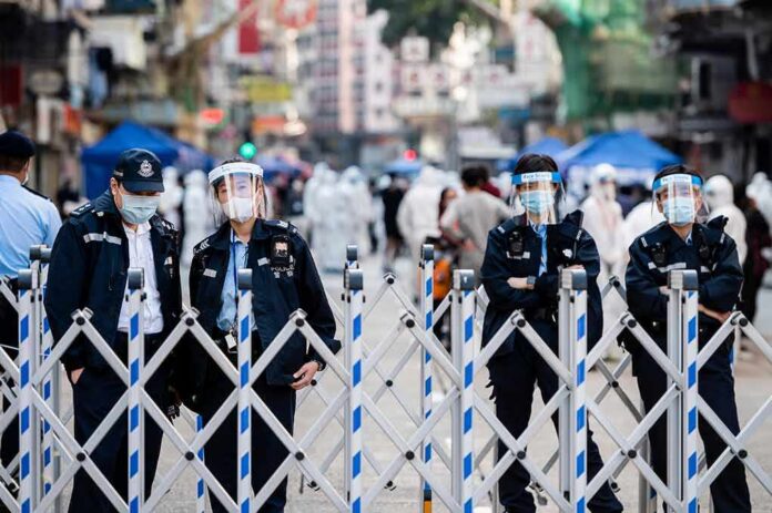 Police officers in masks stand behind portable barricades on a city street