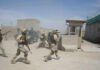 Stunning Bounty Threat For Captured Troops Soldiers in desert uniforms run past a checkpoint amid dust