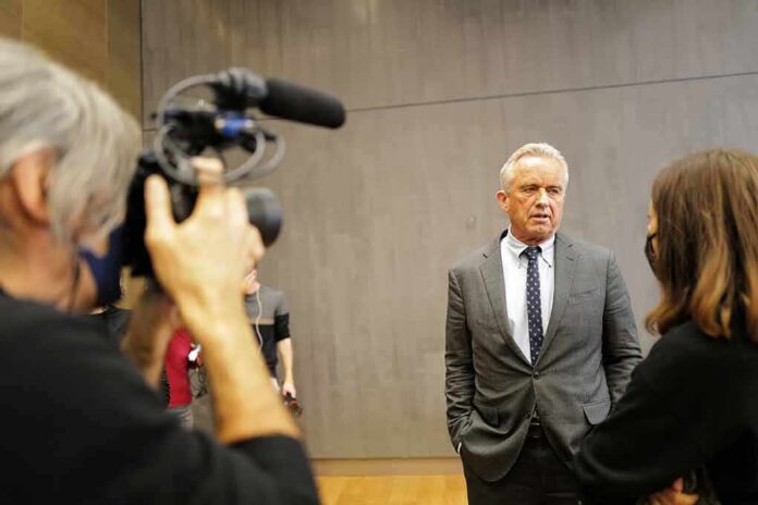 shutterstock_2314962243 Man in a gray suit speaks to a reporter during an interview