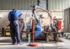 Factory worker operates near an industrial robot arm in a workshop