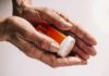 Older hands holding a prescription pill bottle