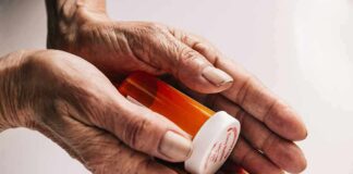 Older hands holding a prescription pill bottle