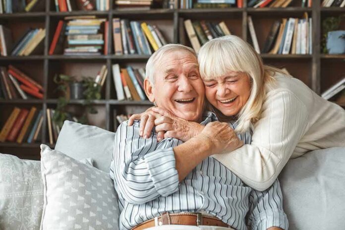 shutterstock_1049436014 Older couple hugging and laughing on a couch