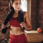 WNBA Guard Torches Viral Sweeney Ad Woman in red workout clothes holding a towel in a gym