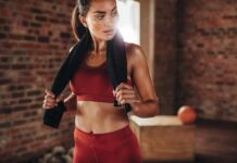 WNBA Guard Torches Viral Sweeney Ad Woman in red workout clothes holding a towel in a gym