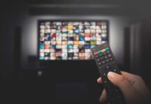 Living Room Wiretap? LG Fights Explosive Claim Hand holding TV remote toward a screen with streaming thumbnails