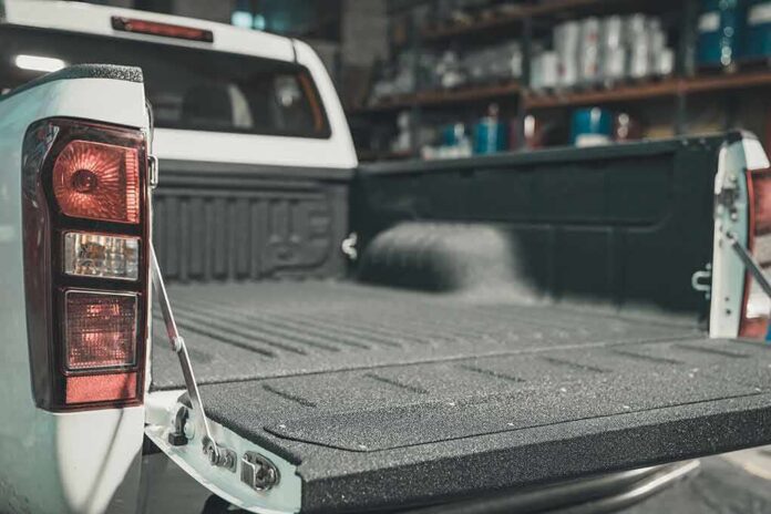 shutterstock_1557234365 Pickup truck bed with open tailgate in a workshop
