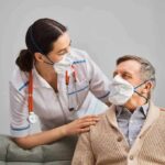 FDA Shifts Alzheimer’s Playbook nurse with stethoscope comforting elderly man wearing masks