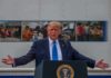 Rate-Cut Standoff: Trump Dangles Trade Freeze Donald Trump speaks at a podium with arms outstretched