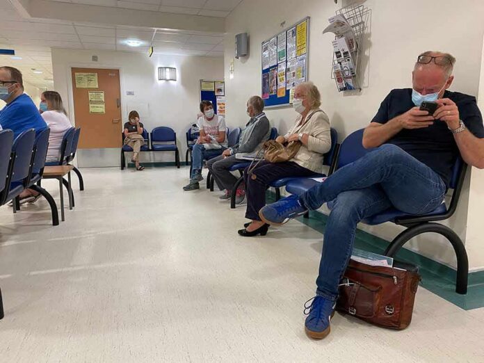shutterstock_1815365642 People wearing masks seated in a hospital waiting room
