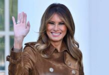 Melania Trump waving and smiling in a brown suede coat