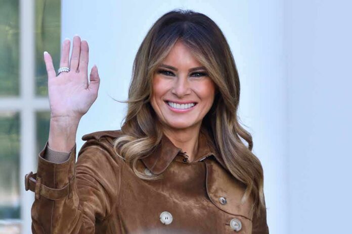 shutterstock_1820907728 Melania Trump waving and smiling in a brown suede coat
