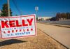 Political campaign yard sign beside a suburban road