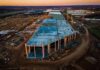 Trump’s $15B Steel Bombshell aerial view of large industrial building under construction at sunset
