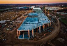Trump’s $15B Steel Bombshell aerial view of large industrial building under construction at sunset