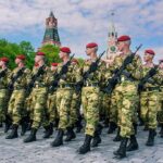 Soldiers in camouflage uniforms march in formation with rifles