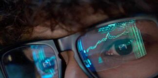 Close-up of a persons eyes with financial data reflected in their glasses