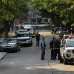 Hanging Death Hunt Intensifies Police officers secure a residential street with patrol cars and yellow tape