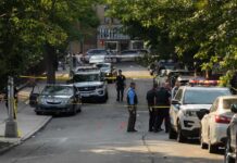 Hanging Death Hunt Intensifies Police officers secure a residential street with patrol cars and yellow tape