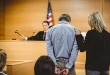 Russian Fraudster Exploits Election Loopholes Defendant in handcuffs stands before a judge in a courtroom