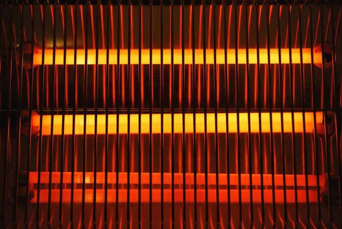 Electric space heater with glowing heating elements behind a safety grille