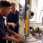 Student operating a bandsaw under instructor supervision