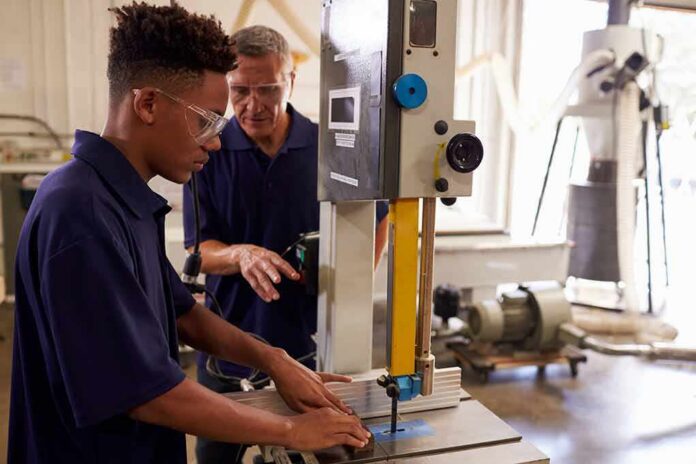 Student operating a bandsaw under instructor supervision