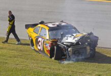 Racing Icon’s Mystery Brain Battle Race car with heavy front-end damage on grass
