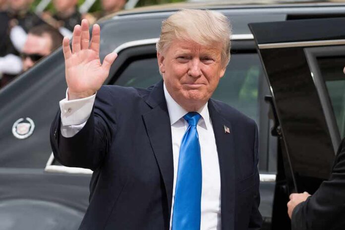 shutterstock_677126326 Donald Trump waves while standing beside a black vehicle