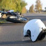 Motorbike Swarms Lock Down Iran White motorcycle helmet on road with fallen bike in background