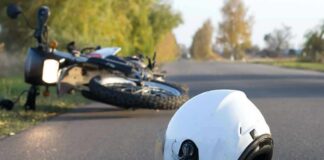 White motorcycle helmet on road with fallen bike in background