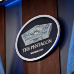 Trump Greenlights Firing Squad The Pentagon emblem between two flags.